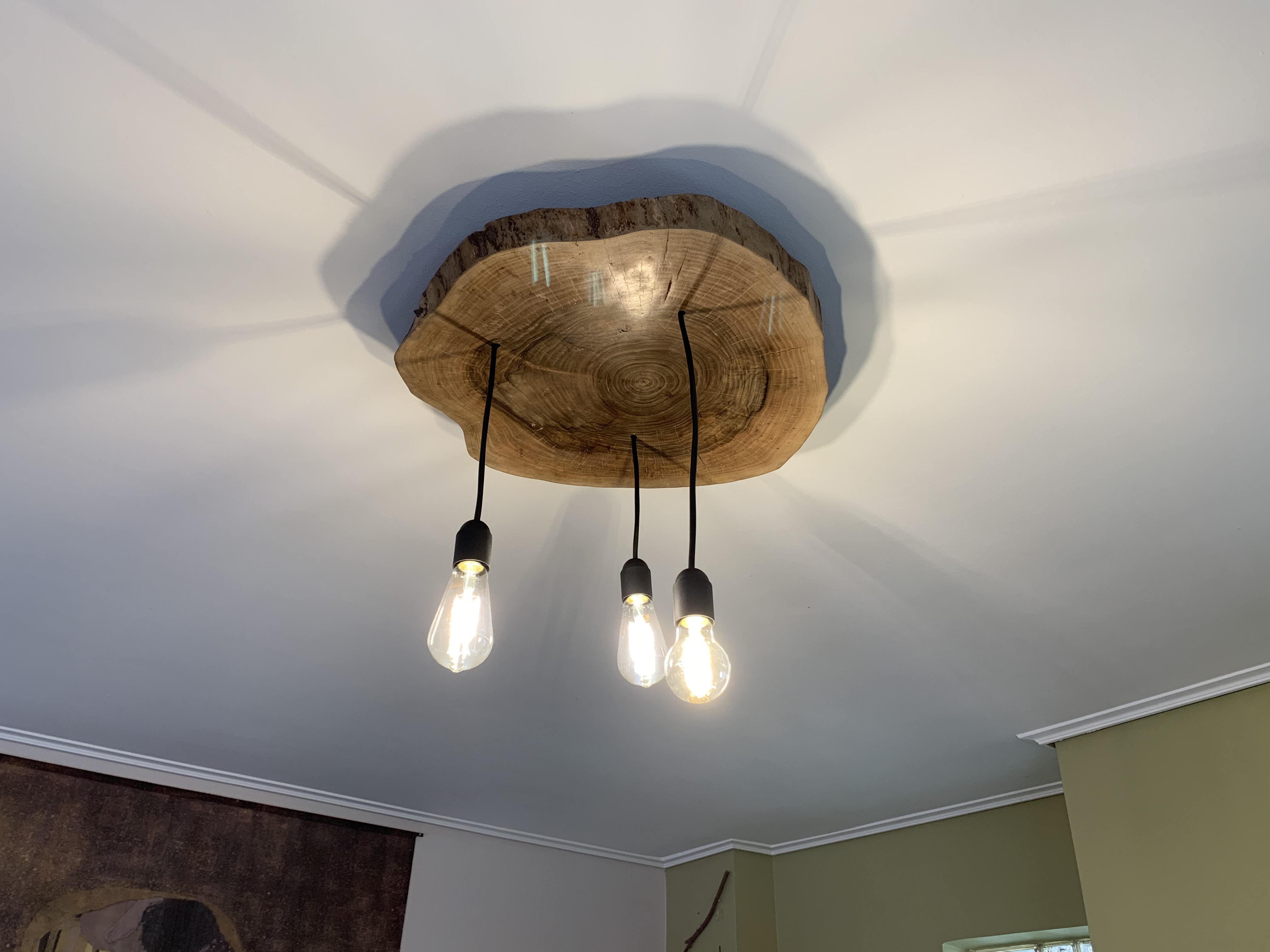 First rooftop light installed — walnut canopy with three Edison filament bulbs